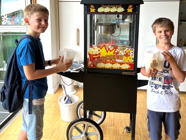 Zwei Jungs vor einem Wagen mit Poppcorn